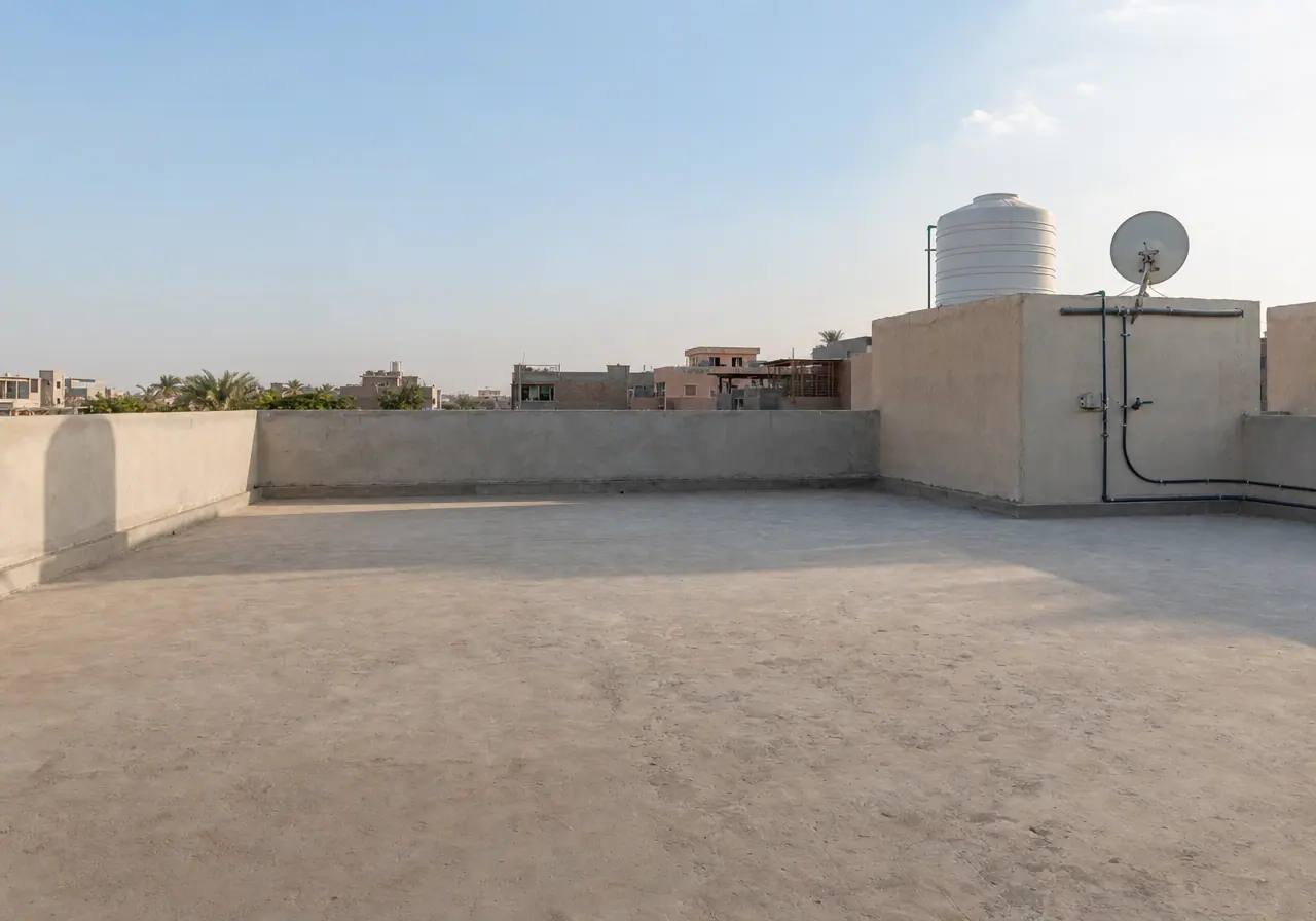 A bare concrete rooftop before styling, empty except for a water tank